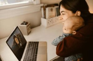 This image depicts a smiling mother and child video calling with her husband on a laptop, depicting another way how telecom investment benefits the military. 